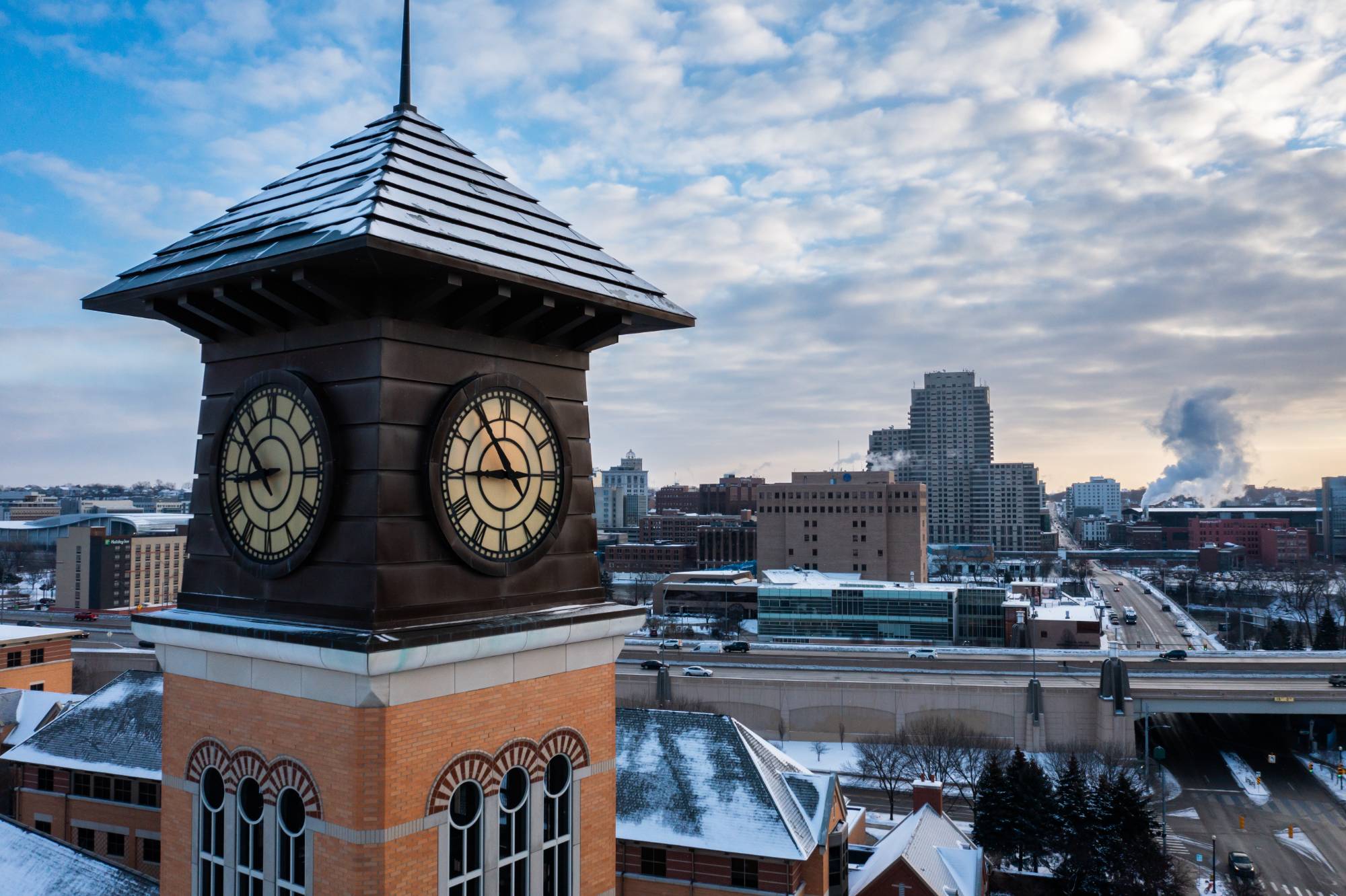 Clock tower in front of aerial view of downtown campus